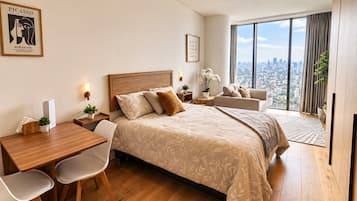 Un dormitorio moderno con una cama grande, un escritorio y vistas de la ciudad.