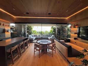 Cozinha moderna com ilha central, bancada para refeições e uma grande televisão.