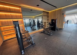 Uma academia com equipamentos de ginástica, espelho e painéis de madeira.