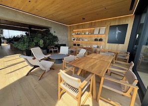 Un interior moderno con una zona de comedor de madera, asientos y una pared con estanterías que exhiben objetos decorativos.