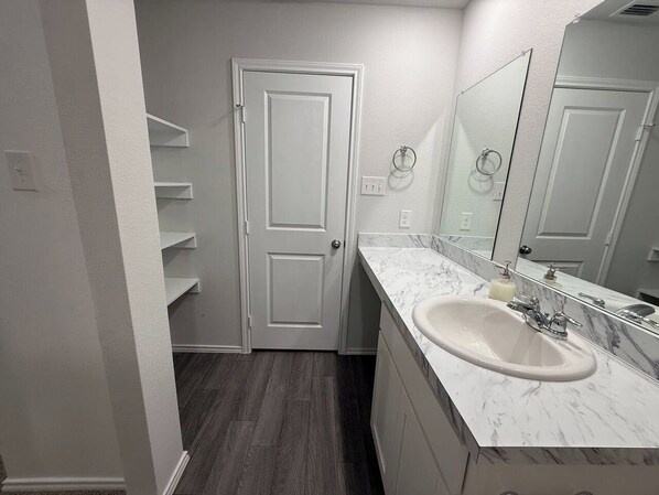 Un baño con una puerta blanca, un lavabo de mármol y un espejo.