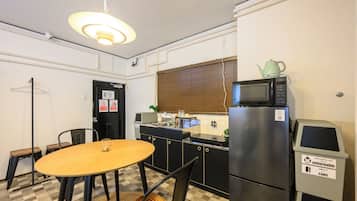A compact kitchen with a microwave, refrigerator, and a small dining table with chairs.