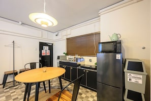 A compact kitchen with a microwave, refrigerator, and a small dining table with chairs. - Zeroichi Hotel Art Ohori  (Fukuoka)
