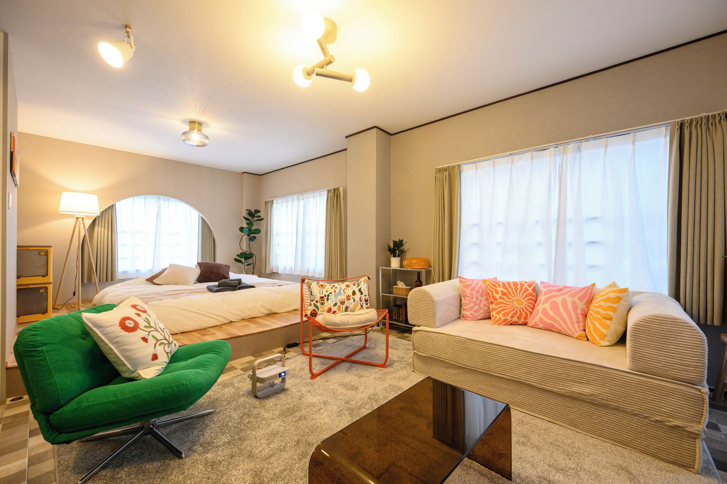 A hotel room with a bed, a green chair, a sofa, and a small table.