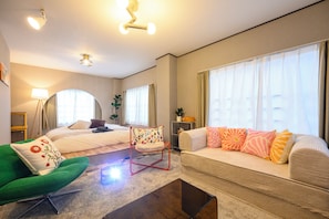 A hotel room with a bed, a sofa, a green armchair, a coffee table, and a floor lamp. - Zeroichi Hotel Art Ohori  (Fukuoka)