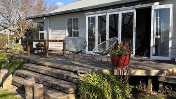 A house with a wooden deck, two chairs, and a potted plant.