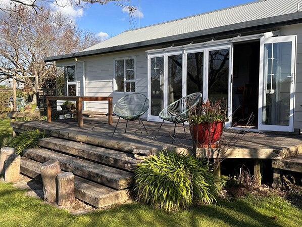 A house with a wooden deck, two chairs, and a potted plant.