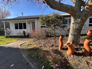 A house with a porch, a tree, and terracotta pots.