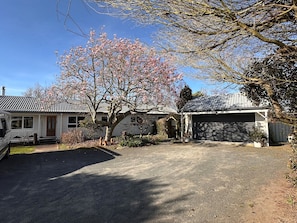 A residential driveway with a garage, a parked vehicle, and a tree with pink blossoms.