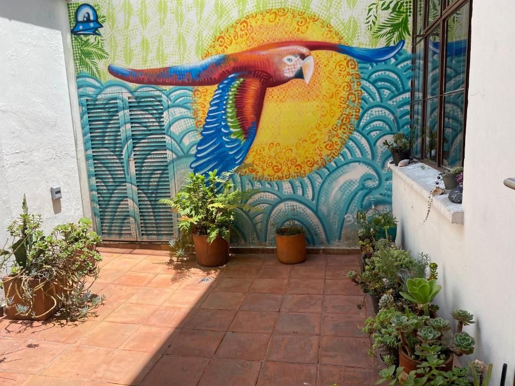A mural of a parrot on a wall, potted plants, and a tiled patio area.