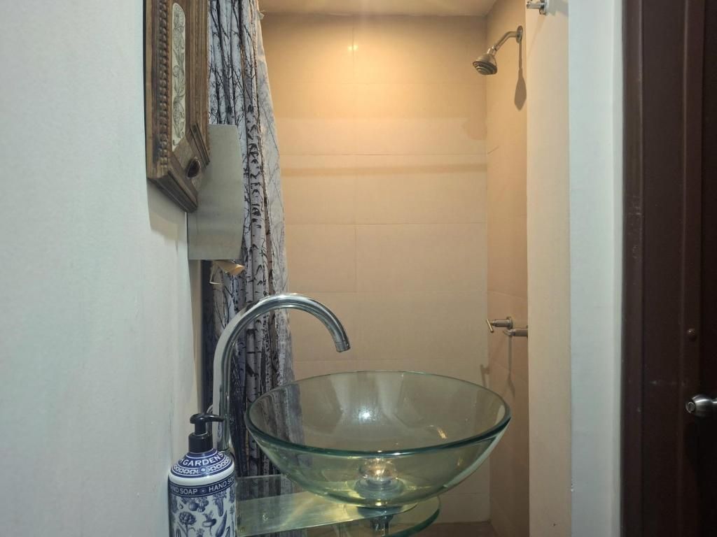 Une salle de bain avec un lavabo en verre, une douche et une porte.