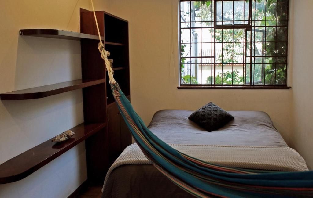Una habitación con cama, una hamaca, una ventana con vistas y un estante.