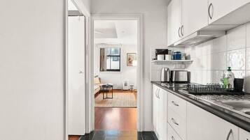 A modern kitchen with white cabinets, a black countertop, and a stainless steel kettle.