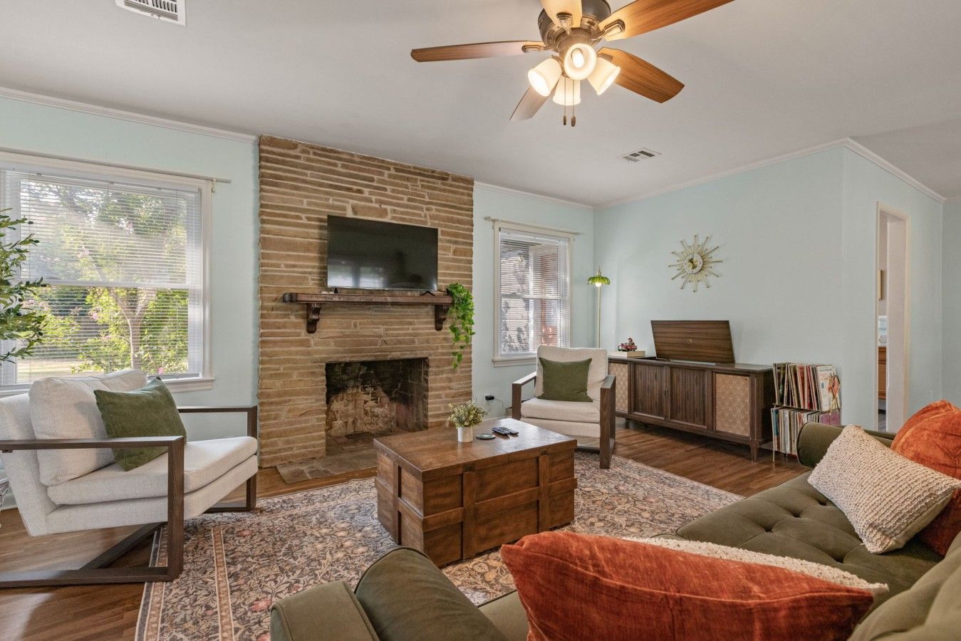 A living room with a fireplace, a ceiling fan, and a television.