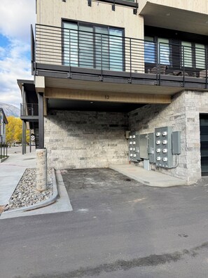 A modern building with a stone facade, a metal balcony, and a parking area with utility boxes. - Mountain getaway near Keystone, Breckenridge & Copper! Walk to shops & dining. (Silverthorne)