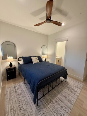 A bedroom with a bed, two bedside tables, a ceiling fan, a mirror, and a door. - Mountain getaway near Keystone, Breckenridge & Copper! Walk to shops & dining. (Silverthorne)