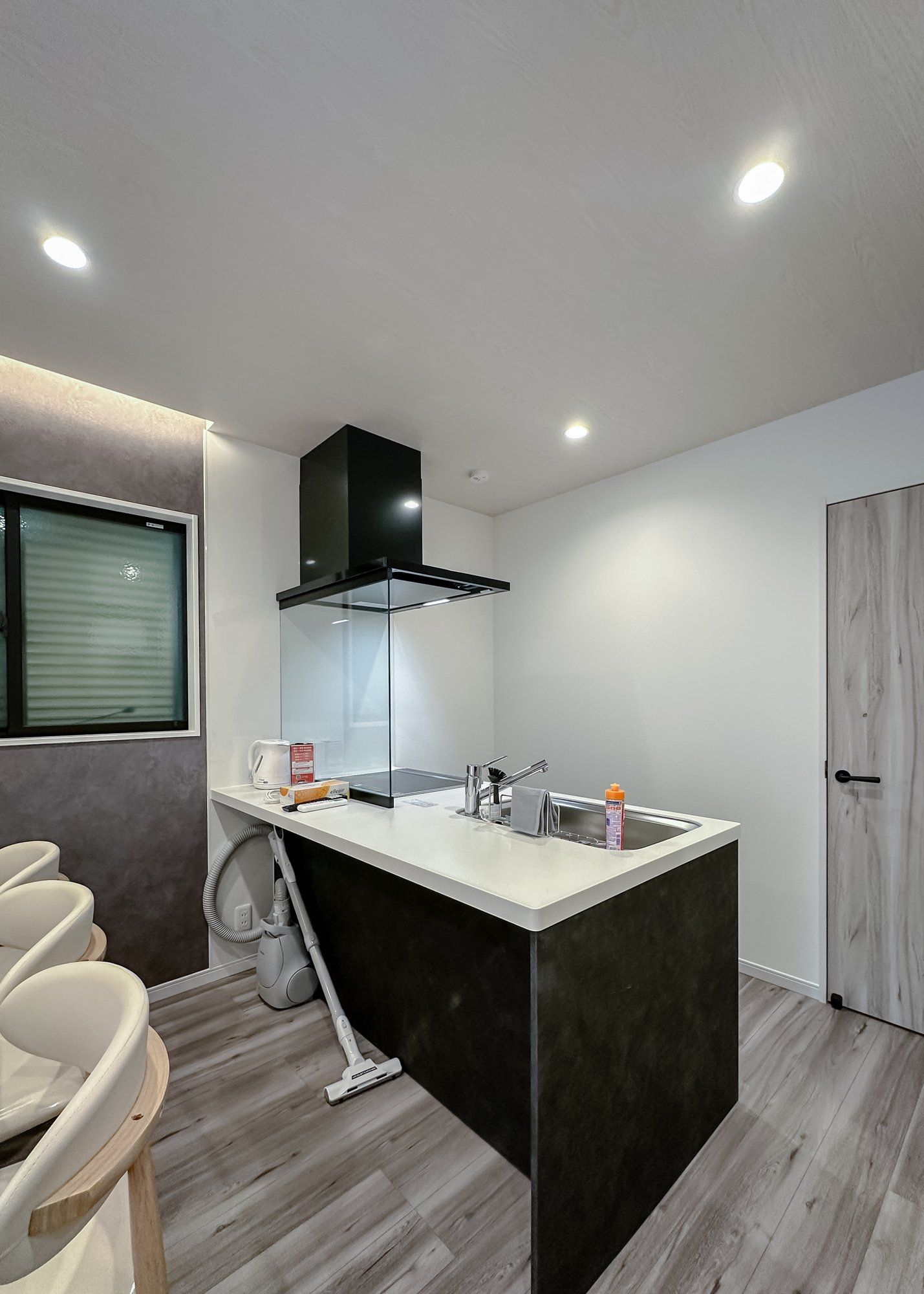 A modern kitchen with a central island, built-in appliances, and a window with blinds.