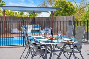 An outdoor patio with a pool, a covered seating area, and a table set for dining. - The Blue House Spacious Home (Port Macquarie)