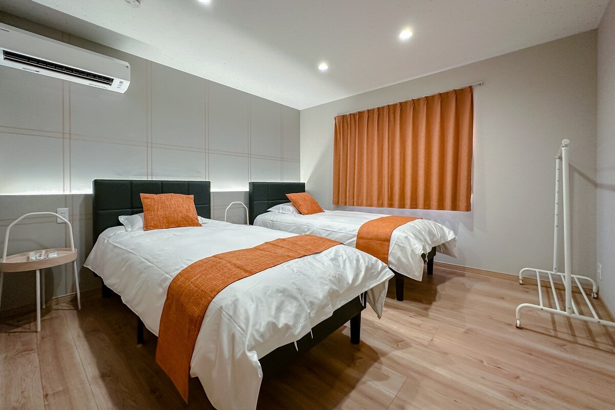 Ein modernes Hotelzimmer mit zwei Betten, einem Heizlüfter und einem fenster mit Vorhängen.