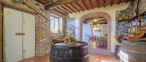 A rustic interior with exposed brick walls, wooden beams, and a large barrel in the center.