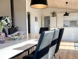 A modern kitchen with white cabinets, a dining area with a table and chairs, and pendant lighting. - 8 Person Holiday Home in Hirtshals (Hirtshals)
