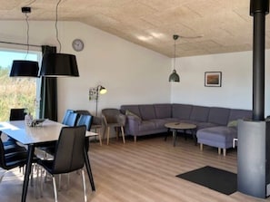 A modern living room with a dining table, sofas, and a fireplace. - 8 Person Holiday Home in Hirtshals (Hirtshals)