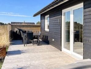 A wooden deck with outdoor furniture, a sliding glass door, and a view of the surrounding area. - 8 Person Holiday Home in Hirtshals (Hirtshals)