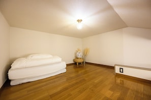 A room with a bed, a fan, and a vase with dried plants. - Haku Loft Hakata 202 (Fukuoka)