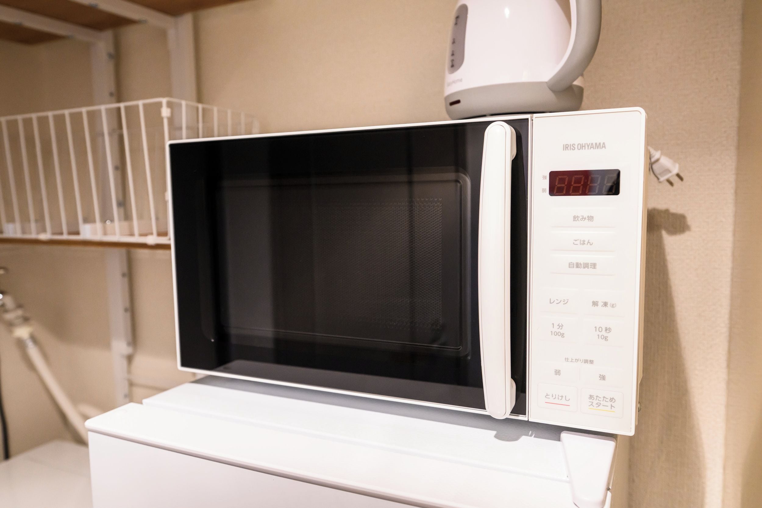 A white microwave oven with a digital display on a white countertop.