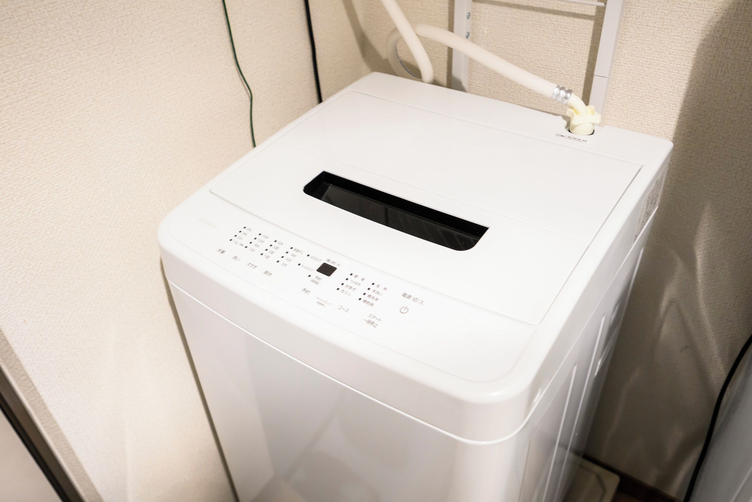 A white, compact, front-loading washing machine with a control panel featuring multiple buttons and a digital display.