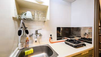 A kitchen with a stainless steel sink, a dish rack, a stove, and a faucet.