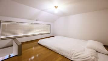 A room with a bed, a ceiling fan, and a window with blinds.