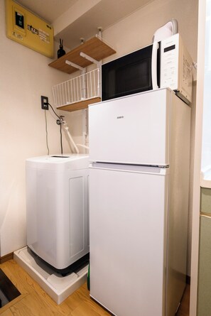 Una cocina compacta con un refrigerador blanco, un microondas y una lavadora.