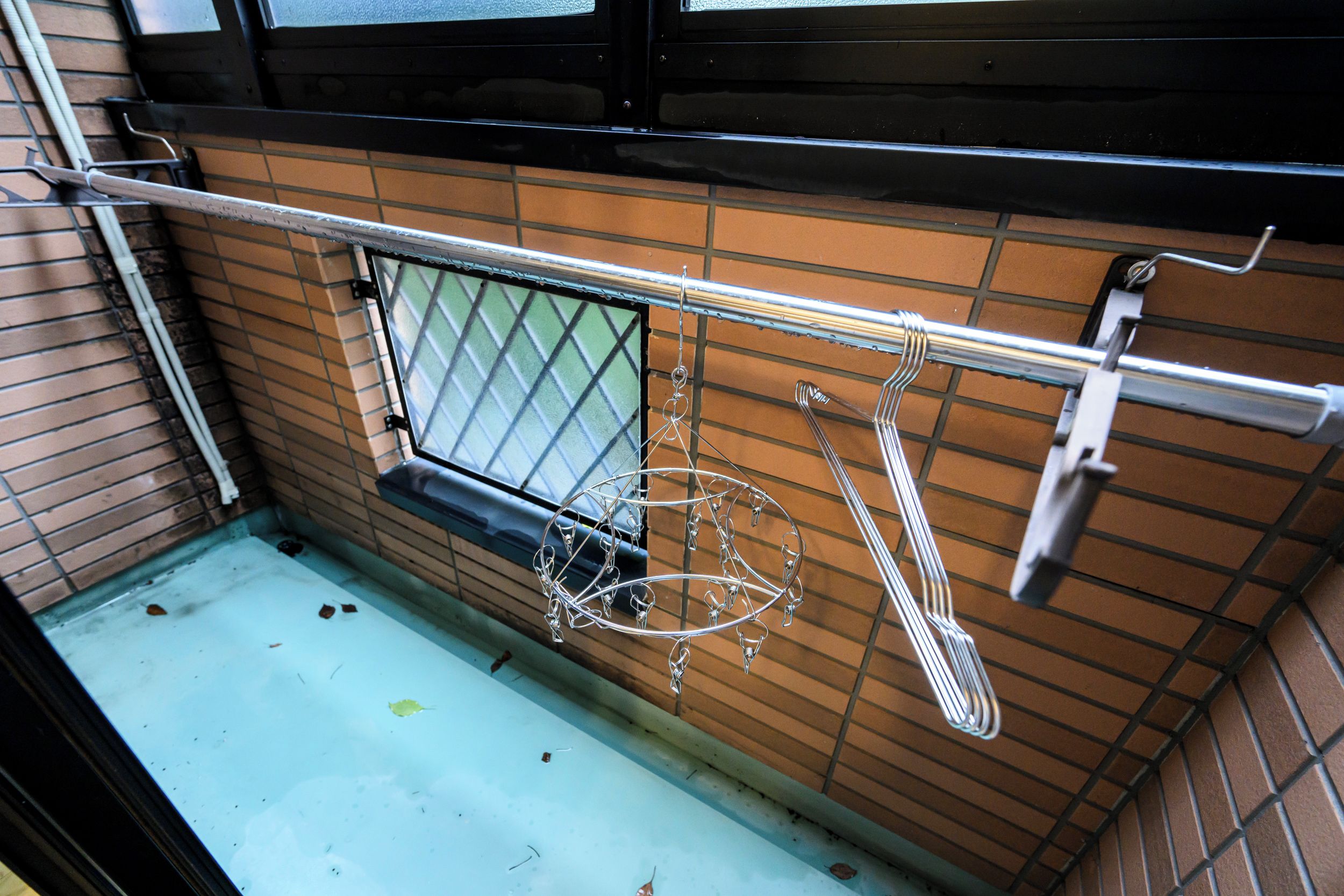 A kitchen with a metal rack holding utensils, a window with a metal grid, and a tiled backsplash.