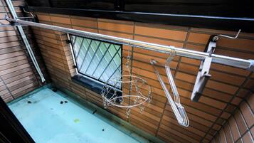 A kitchen with a metal rack holding utensils, a window with a metal grid, and a tiled backsplash.