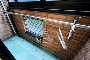 A kitchen with a metal rack holding utensils, a window with a metal grid, and a tiled backsplash. - Haku Loft Hakata 202 (Fukuoka)