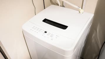 A white, compact, front-loading washing machine with a control panel featuring multiple buttons and a digital display.