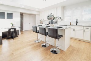 Una cucina moderna con isola centrale, sgabelli da bar e mobili bianchi.