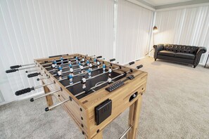 A foosball table in a room with a sofa and a lamp. - Spacious Meridian Hills Retreat | Quiet & Private (Meridian Hills)