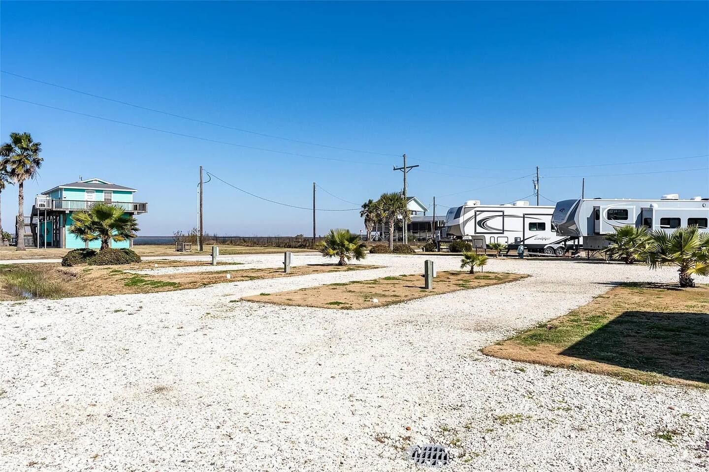 A residential area with a house, palm trees, and a recreational vehicle.