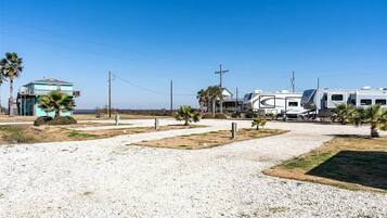 A residential area with a house, palm trees, and a recreational vehicle.