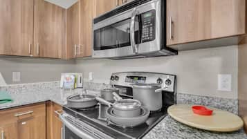 A kitchen with wooden cabinets, a stainless steel microwave, a gas stove, and a granite countertop.