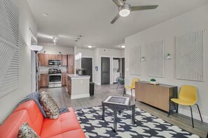 Een moderne woonkamer met een bank, een salontafel en een eethoek met stoelen.