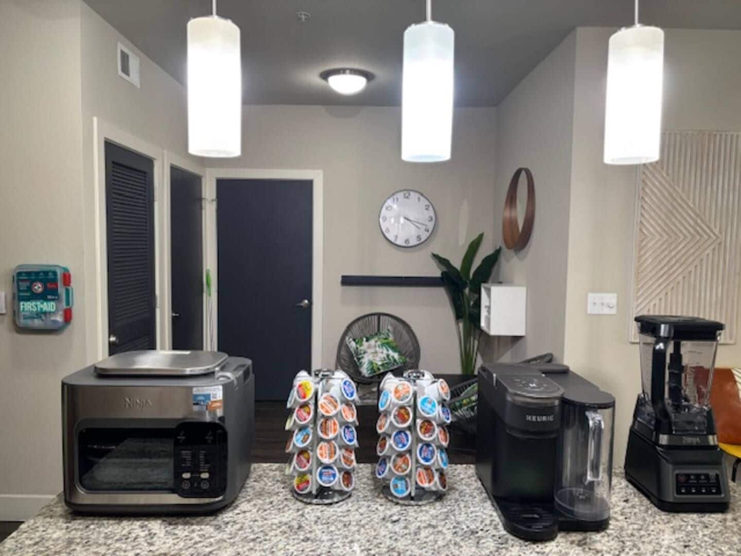 A kitchen with a microwave, coffee maker, blender, and a coffee pod dispenser.