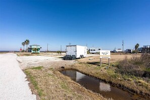 A beachside RV park with a trailer, a stop sign, and a sign for Beach Time RV Park. - Rollover bay RV Spot #5 - pull-through 50/30 amp (Bolivar Peninsula)