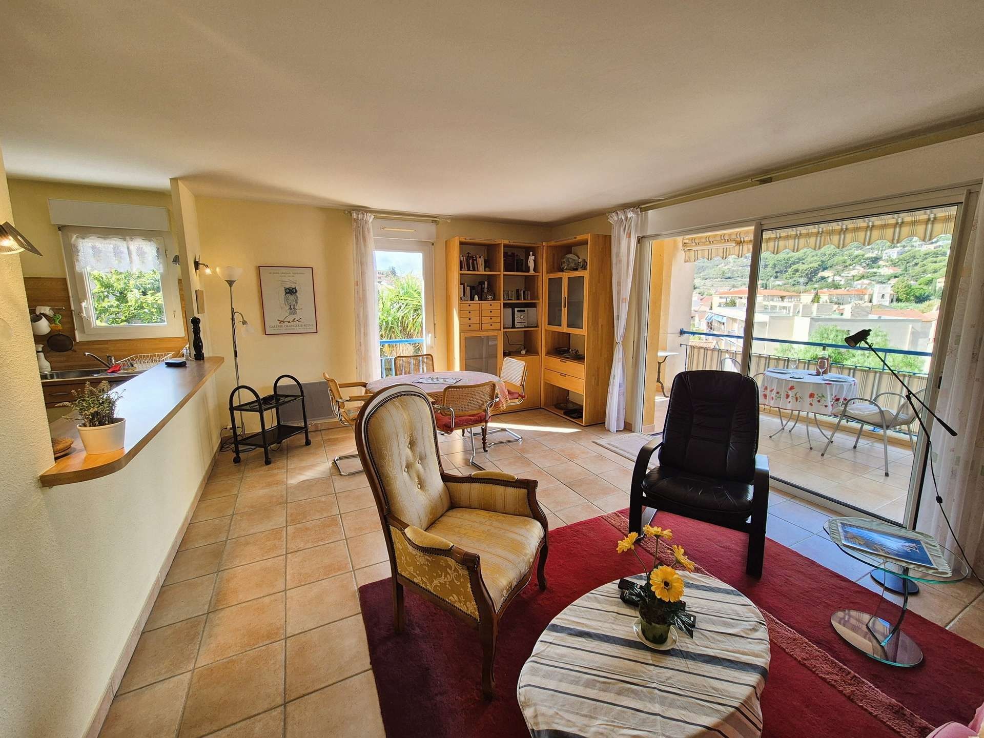 Un salon comprenant un coin repas, une bibliothèque et donnant sur un balcon aménagé avec du mobilier d’extérieur.