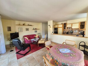 A compact living space with a dining area, a kitchenette, and a seating area with a red sofa and a TV. - 3 rooms, in the heart of Saint Mandrier village (ST MANDRIER SUR MER)