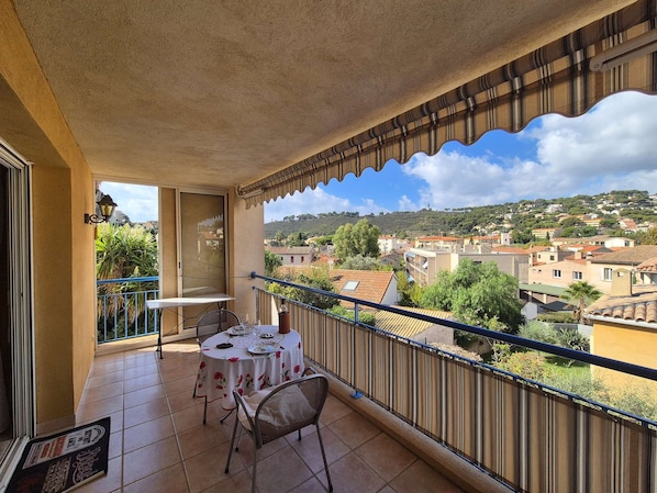 A balcony with a table set for two, overlooking a town with buildings and greenery. - 3 rooms, in the heart of Saint Mandrier village (ST MANDRIER SUR MER)