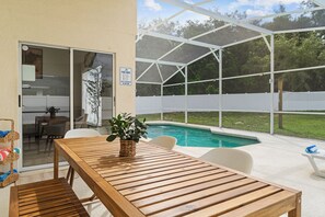 A covered outdoor area with a pool, a wooden table, and chairs. - Spacious 4-bedroom house in lovely Davenport with AC (Davenport)