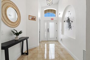 A hallway with a mirror, a potted plant, an exit sign, and a wall art piece. - Spacious 4-bedroom house in lovely Davenport with AC (Davenport)
